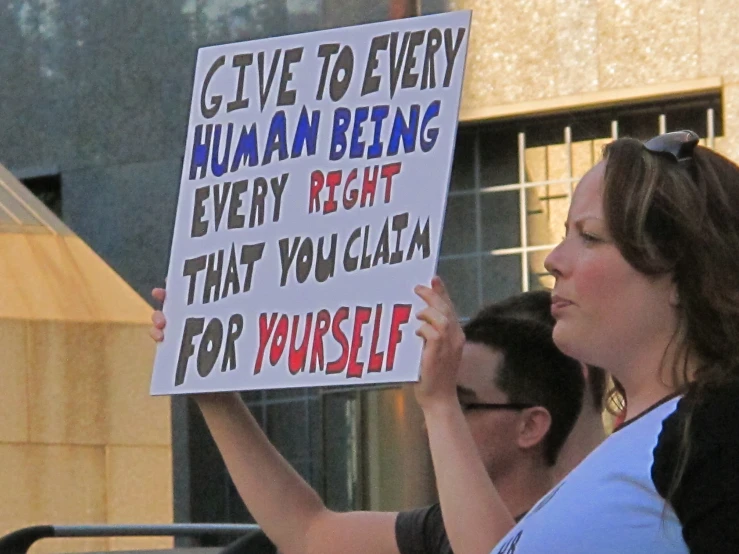 a protester holds a sign while speaking to others outside