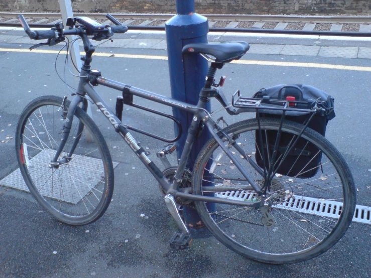 a blue bike that is leaning up against a pole