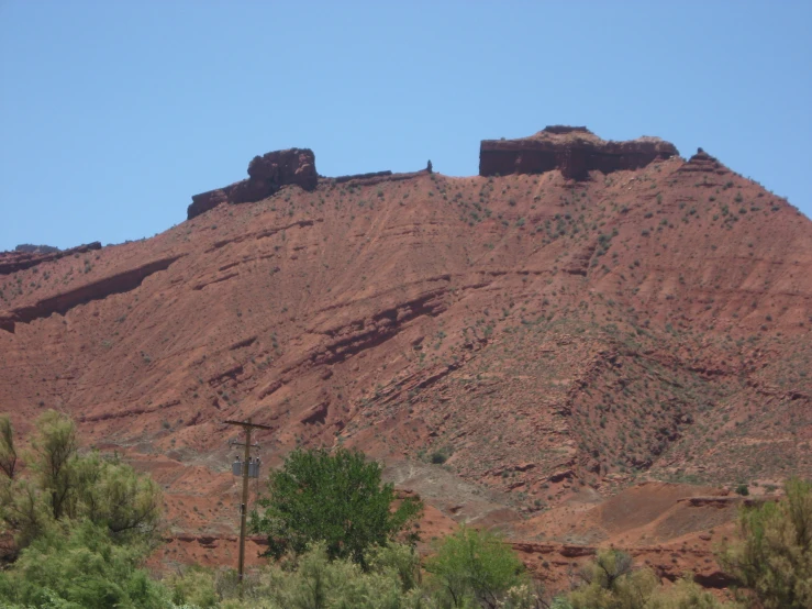 a rocky hill sits in the distance, surrounded by trees