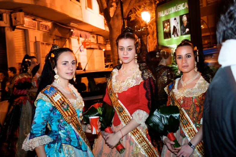 some pretty young women standing together in fancy clothing