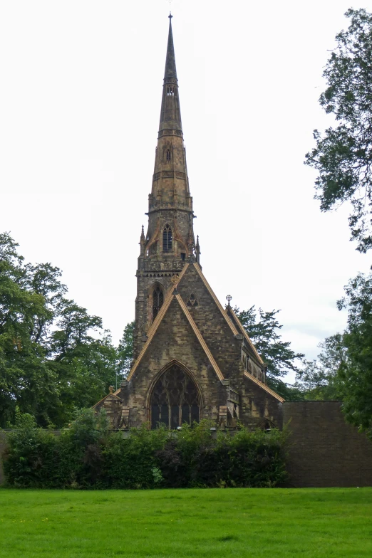 an old, tan brick building with a steeple surrounded by greenery