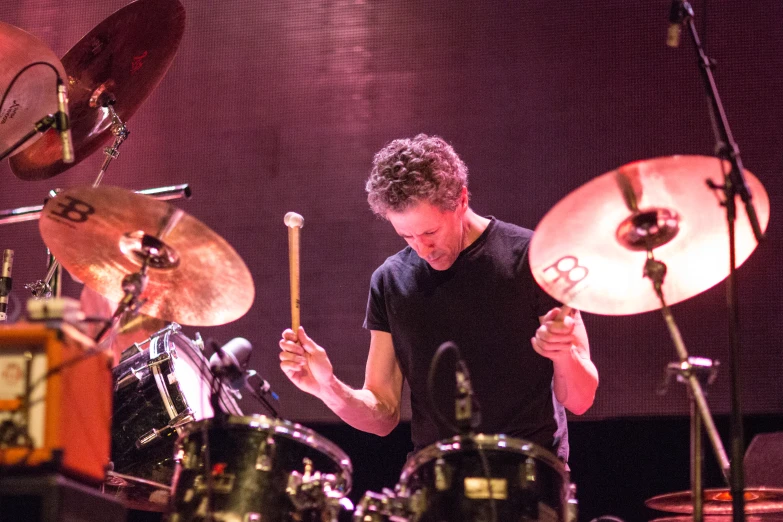 man playing drums in a dark room with lights on