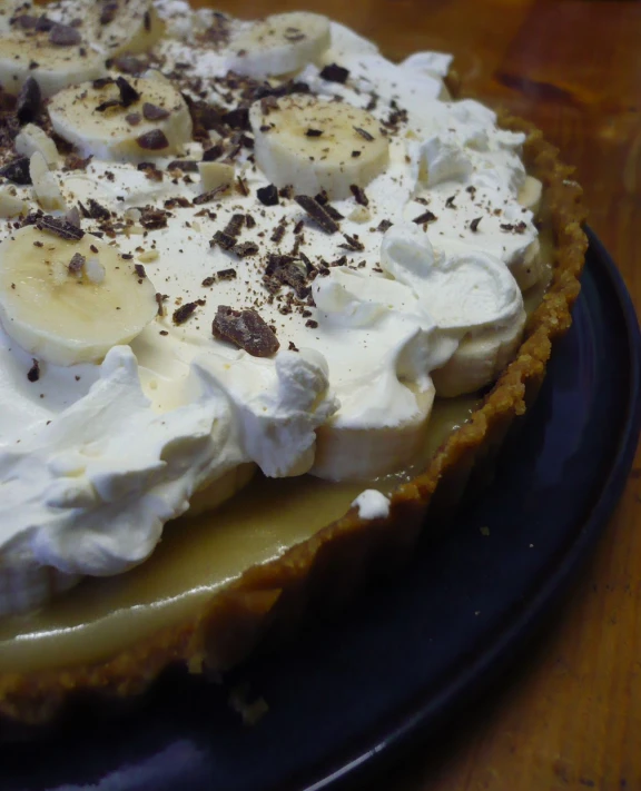 there is a dessert with whipped cream, banana slices and chocolate chips