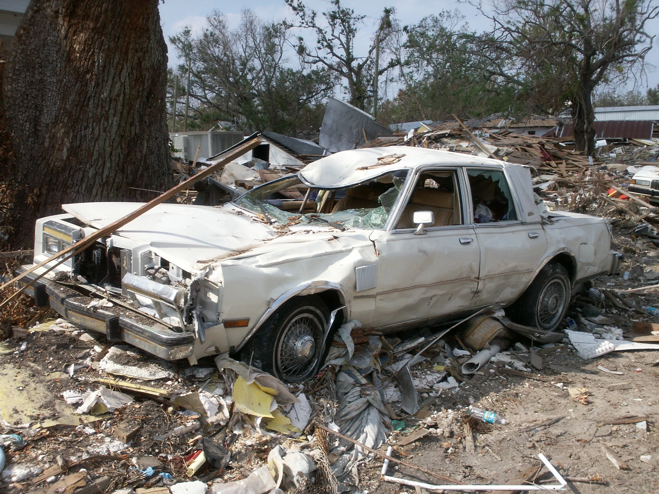 an old vehicle sitting among the rubble next to a tree