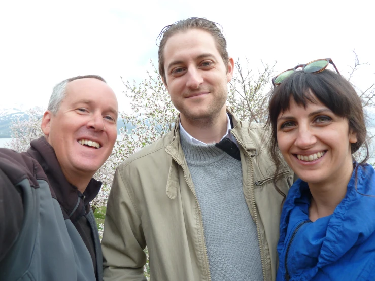 two men and one woman smile together while smiling