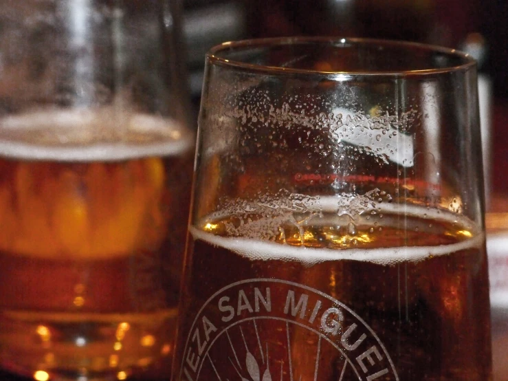 two glasses of beer sitting on top of a table