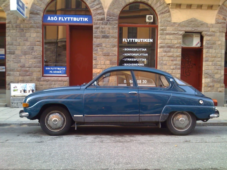 a blue car parked in front of a brick building