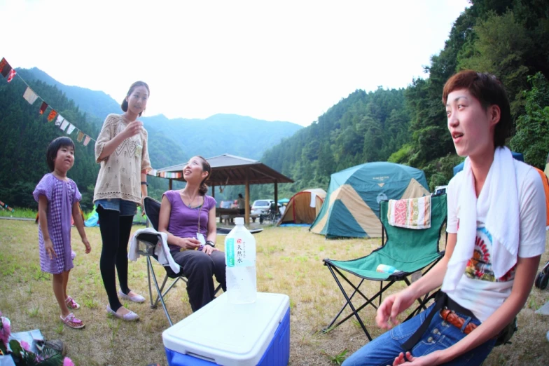 people stand on an open field near a bunch of camping tents