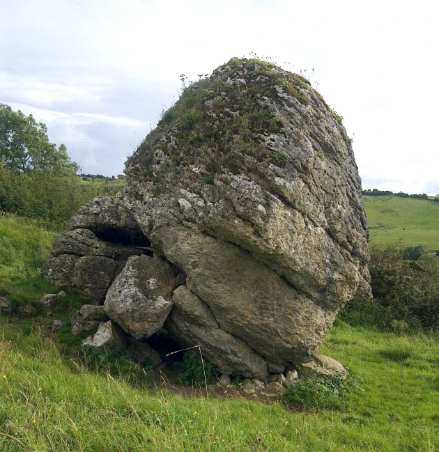 an upturned rock lying in the middle of a field