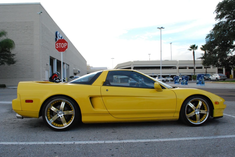 the yellow sports car is parked in the parking lot