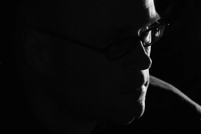 a man is wearing glasses in a darkened room