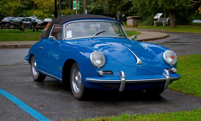 an old classic sports car in the middle of a parking lot