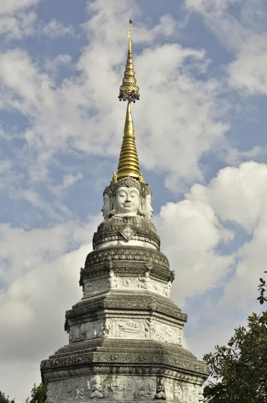 a tower with a gold spire surrounded by trees