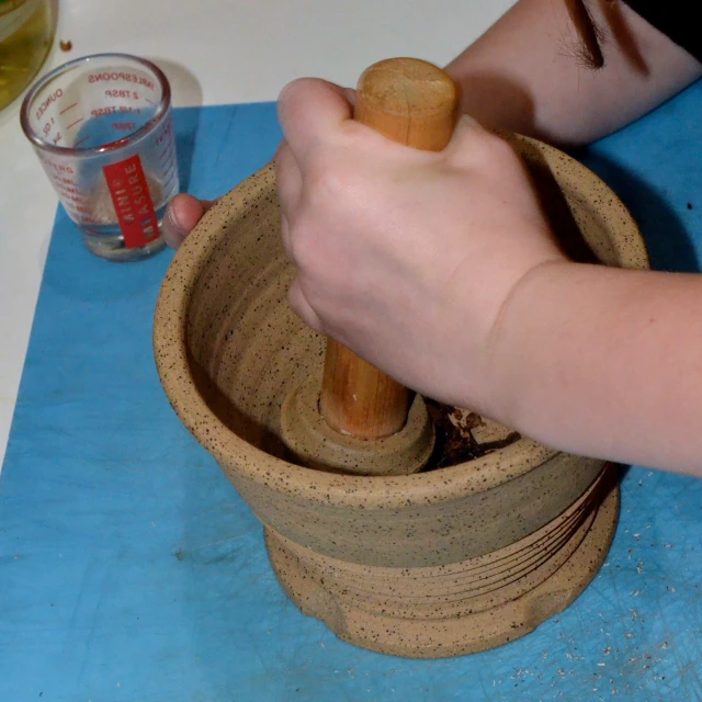 a person spinning wooden objects in a mortar