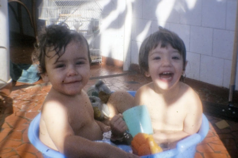 two little s sitting in a blue tub with toy animals