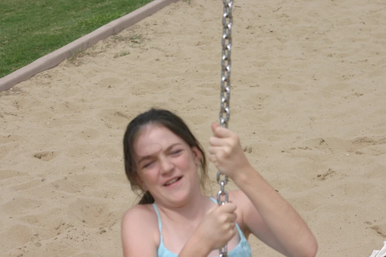 a girl sits in a swing and laughs