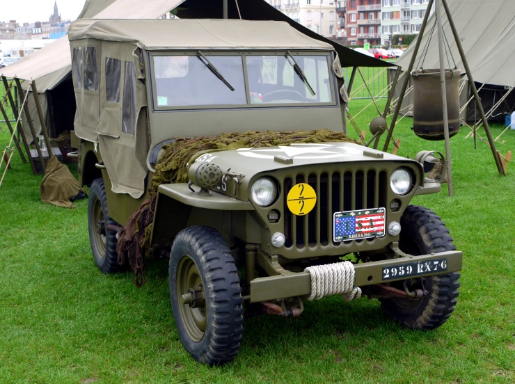 an old army jeep is parked on some grass