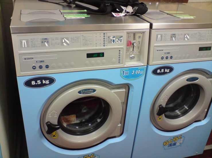 two washing machines with a water bottle next to them