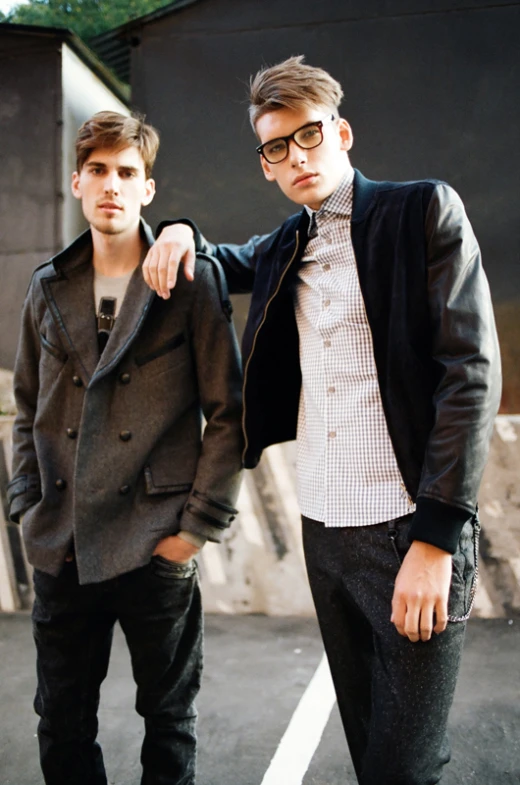 two men are posing together near an old building