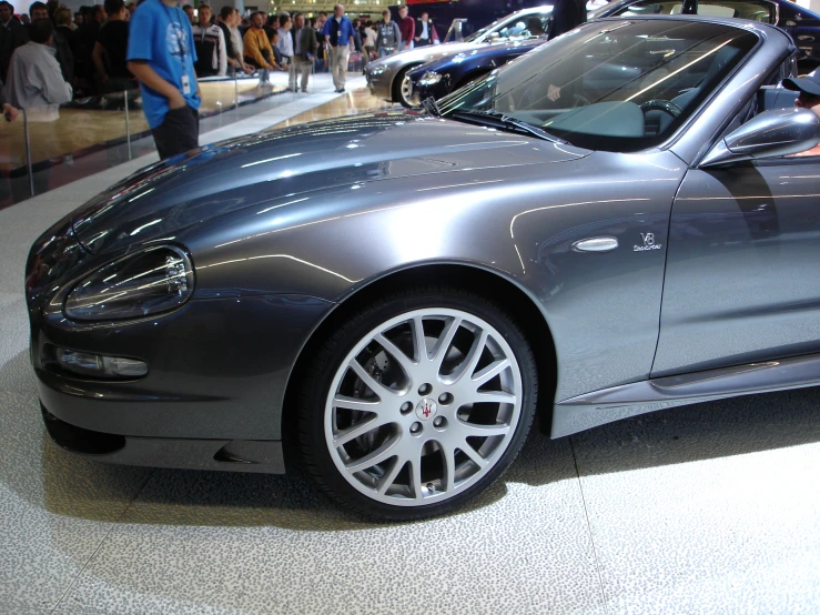 the back view of a silver sports car at a car show