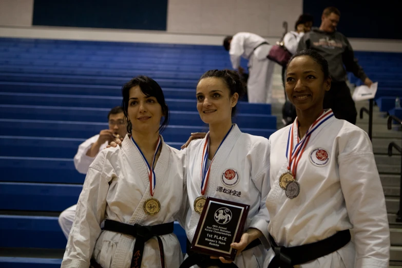 three women smile while holding a plaque and standing next to each other