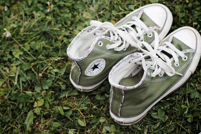 green sneakers with white laces lie on green grass