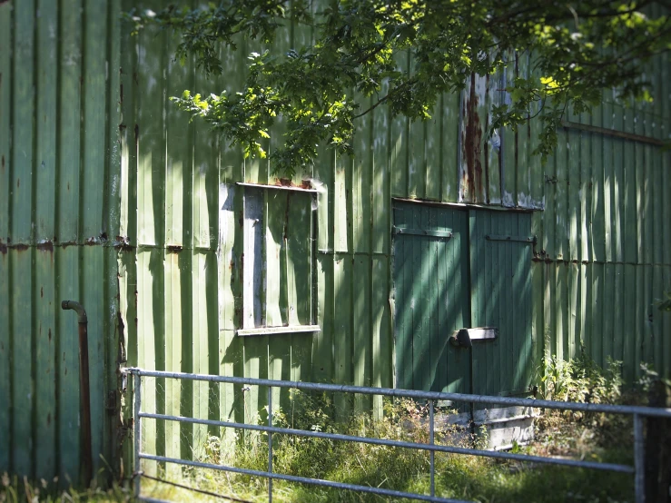 an old green building with some trees next to it