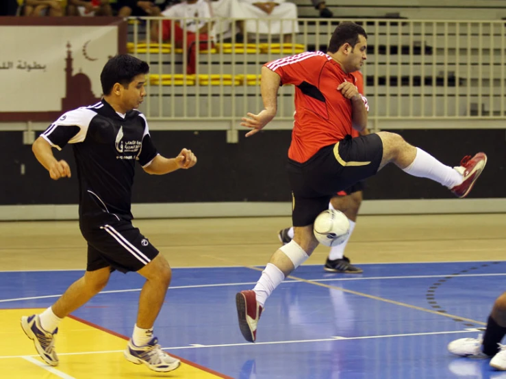 a group of men kicking around a ball on top of a basketball court