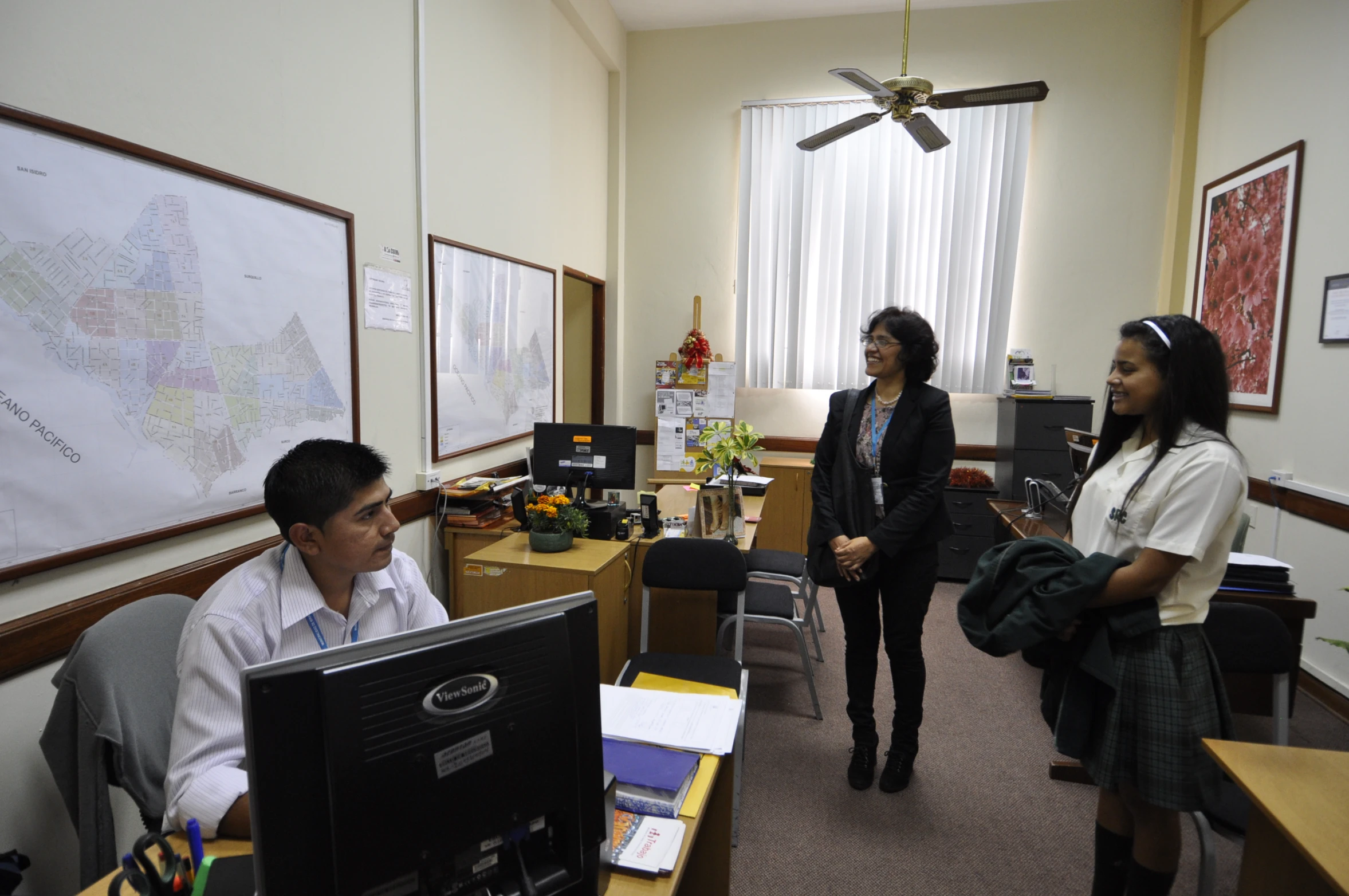 three women talking in a small office area