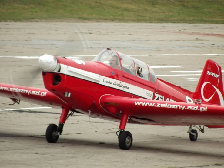 a small red plane sitting on top of an airport runway