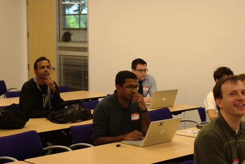 four men working on laptops at their desk