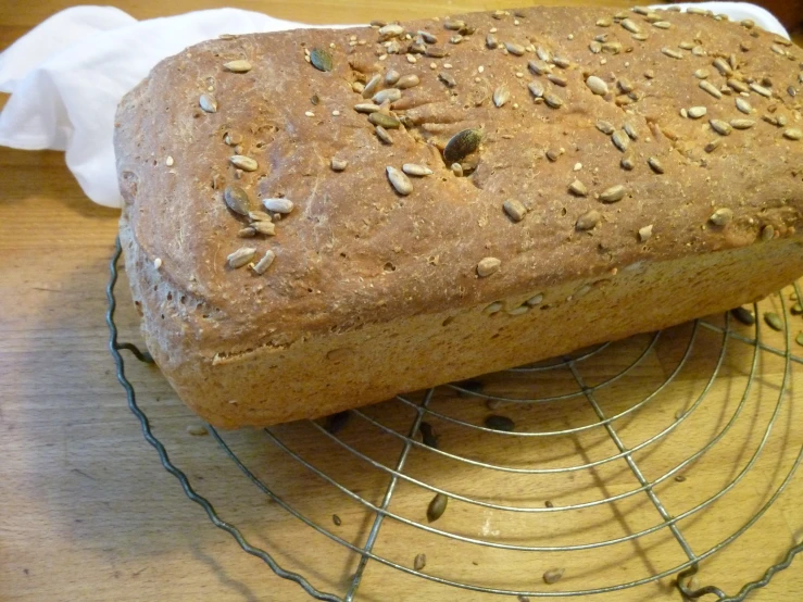 an oat loaf on a cooling rack, with the roll resting on top of it