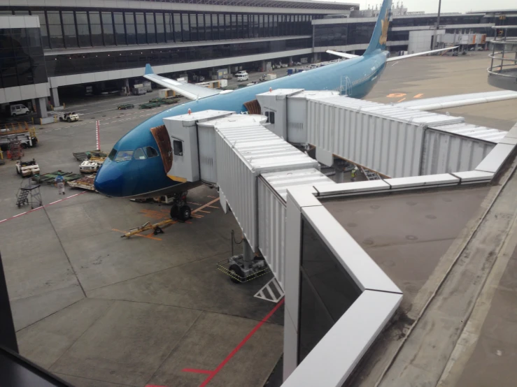 large blue airplane sitting in an airport loading passengers