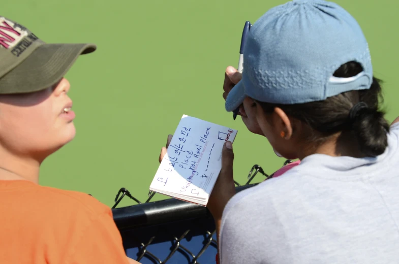 a girl on a tennis court writing on a paper