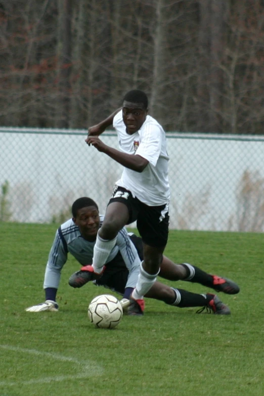 two men playing soccer against each other in the grass