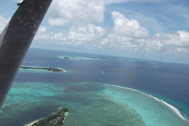 an airplane flying over the ocean with land and water