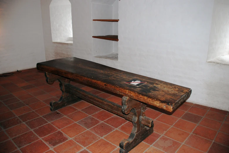 a brown bench sitting on top of a red brick floor