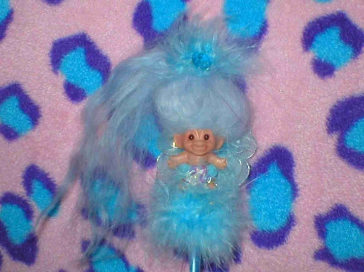 a toy doll on a blue pole with a fluffy purple tail