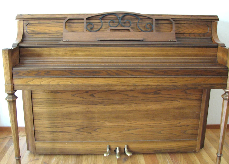 a very old looking wooden piano on a hard wood floor