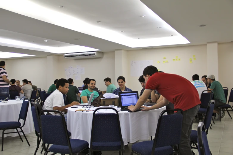 several people sitting at a table working on laptop computers