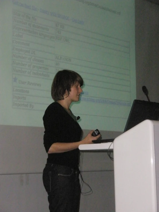 a woman standing in front of a screen giving a lecture