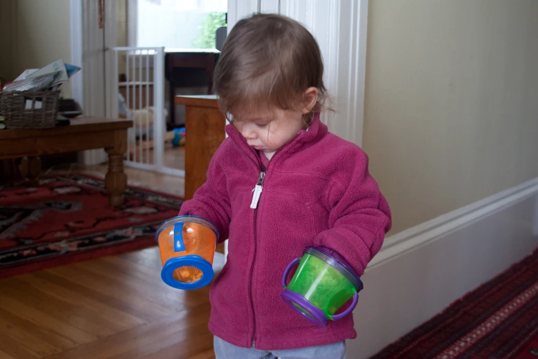 a toddler holds a container with a bright orange design