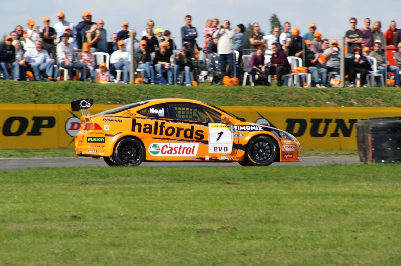 a race car driving on a race track with many people in the bleachers looking on