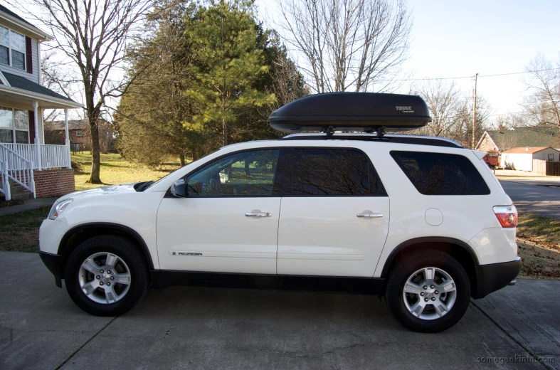 a white suv with a surfboard on the roof