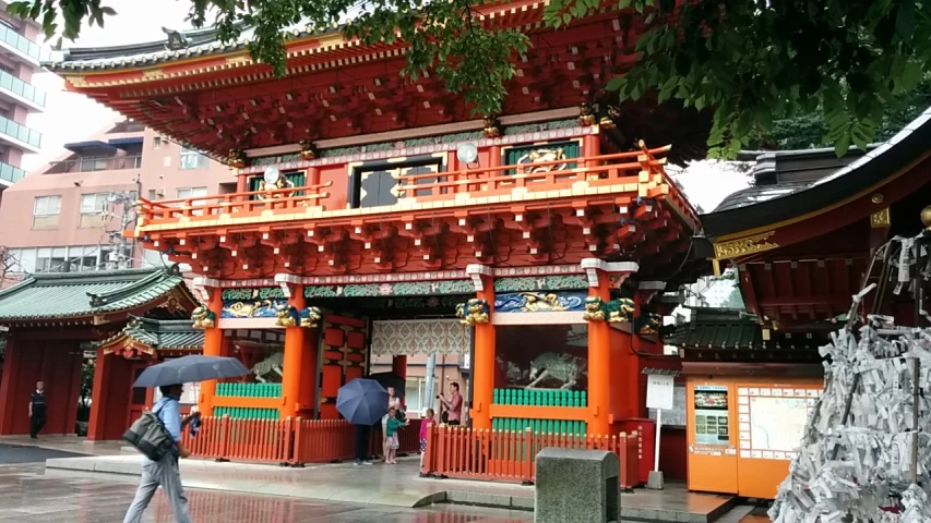 an asian temple with a umbrella, and some people standing under it