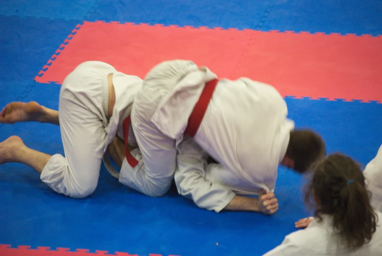 two men with white suits on their faces and legs in a wrestling match