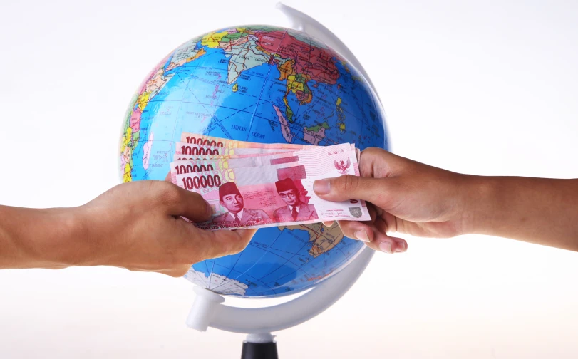 someone is holding cash out to another person in the middle of the globe