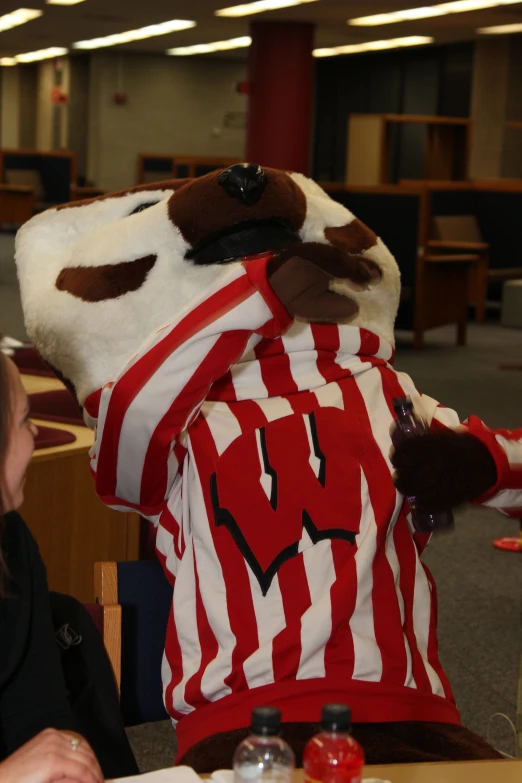 a woman sitting at a desk, wearing a large cow costume