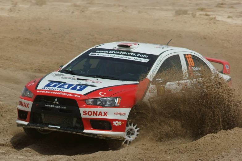 the rally car is kicking up dirt on the track