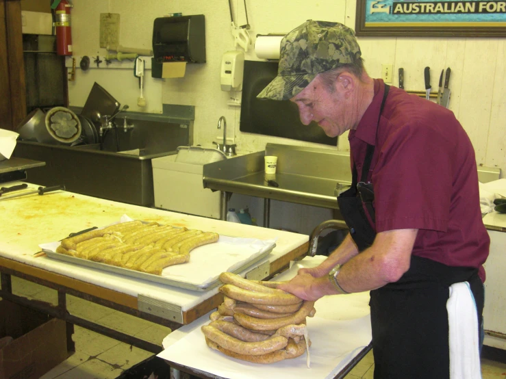 an older gentleman in a kitchen making big sandwiches